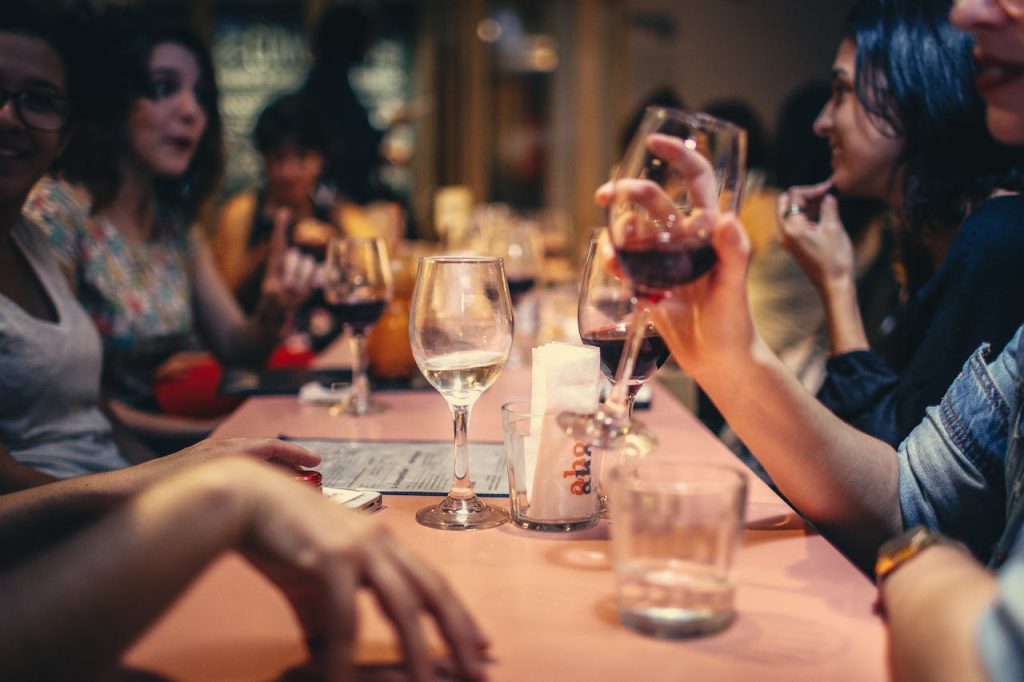 people-drinking-liquor-and-talking-on-dining-table-close-up-photo-696218 A lively scene of friends enjoying wine and conversation in a cozy bar setting.